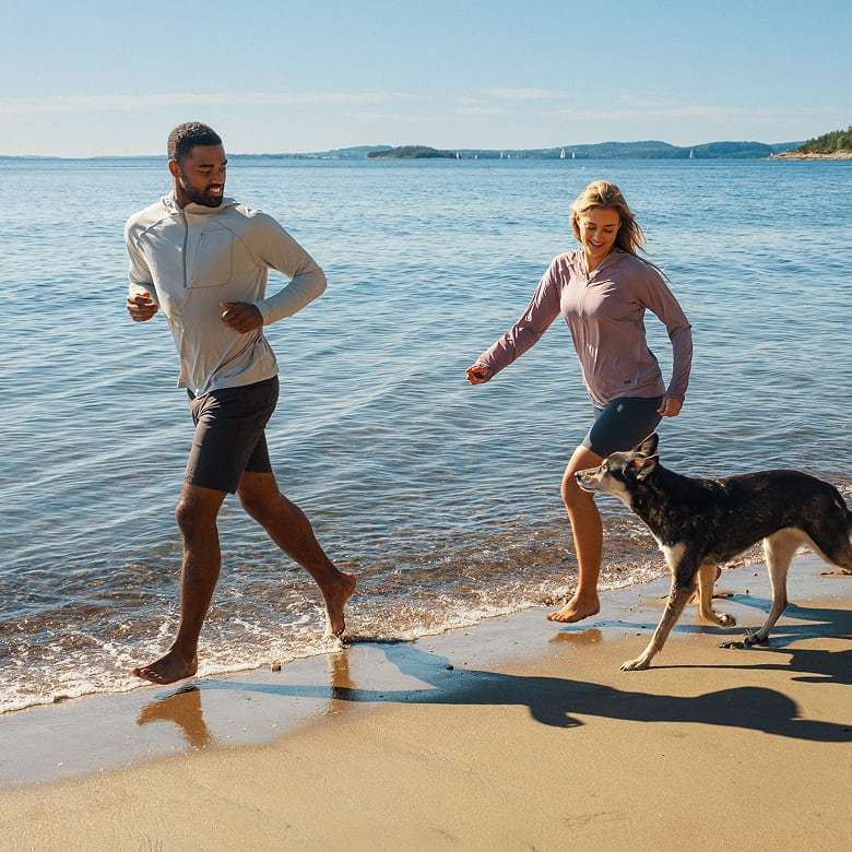 Man and woman with dog on the beach, wearing Helly Hansen sun protective clothing