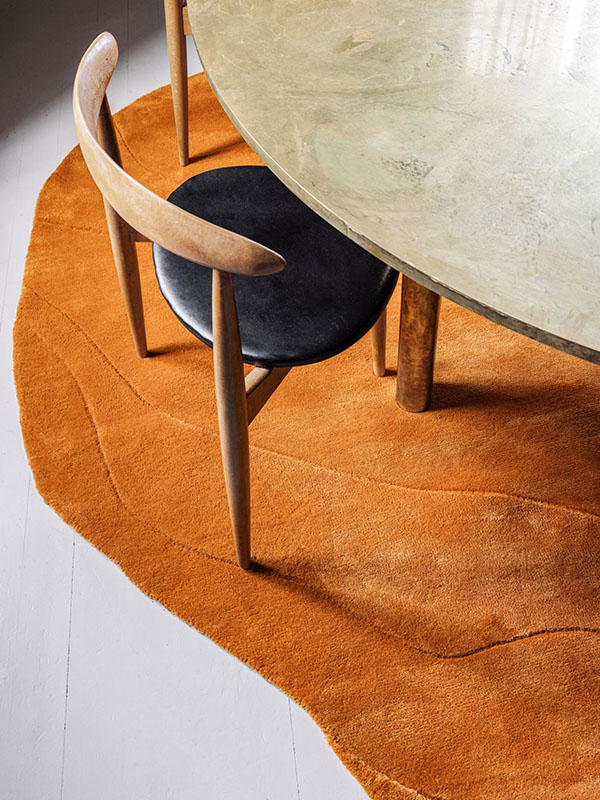 Irregular orange rug under dining table