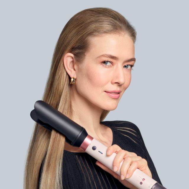 Lo styler asciugacapelli Dyson Airwrap Co-anda2x con l’accessorio Airsmooth2x usato da una modella per lisciare i capelli.