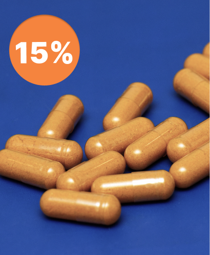 alt="Primo piano di diverse capsule di curcuma giallo-arancione su sfondo blu con etichetta del 15 %"