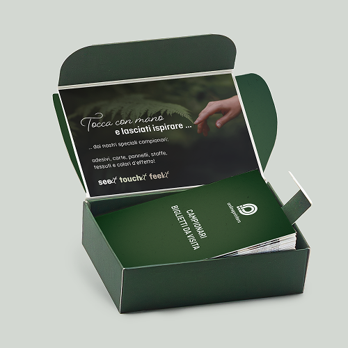 Scatola verde aperta con campioni di biglietti da visita e un opuscolo con la dicitura "Creato per toccare ... i nostri campionari: adesivi, carta, piatti, tessuti, stoffe e colori ad effetto".