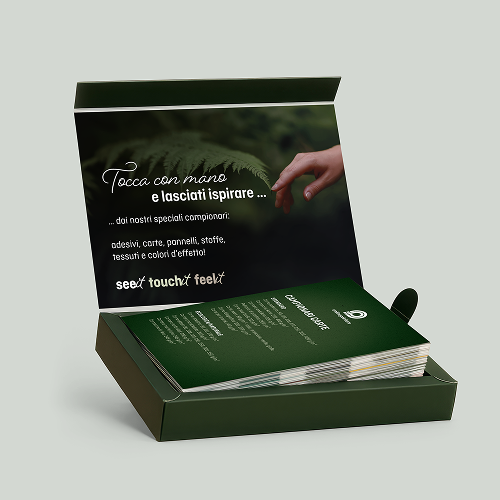 Set di modelli di adesivi, popeline, sintetici, tessuti e colori d'effetto in una scatola verde aperta con il testo “Created to touch” e una mano che si avvicina.