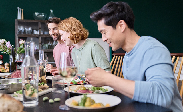 Tre amici che siedono insieme a tavola e mangiano