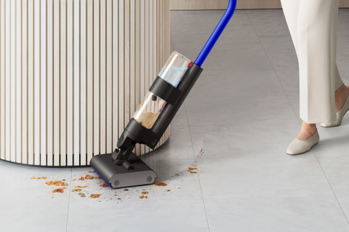 A user cleaning around the edges of a curved kitchen island with the Dyson WashG1 wet cleaner.