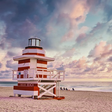 A beach with turquoise water and a Miami Beach lifeguard tower at sunset.
