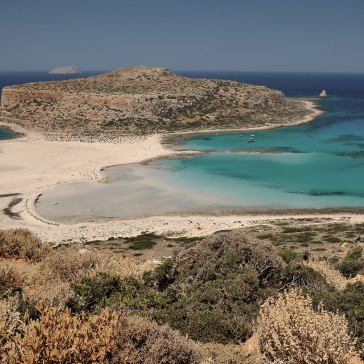 A beach with turquoise water and an island in the background.