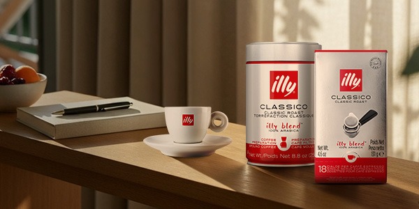 Can of illy coffee on a counter with a woman carrying an illy travel mug