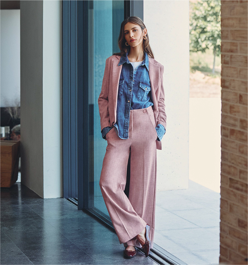 Una donna elegante in un vestito rosa e camicia di jeans, con un look trendy.