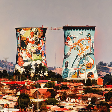 Two artistically painted water towers in Johannesburg with houses and trees in the foreground.