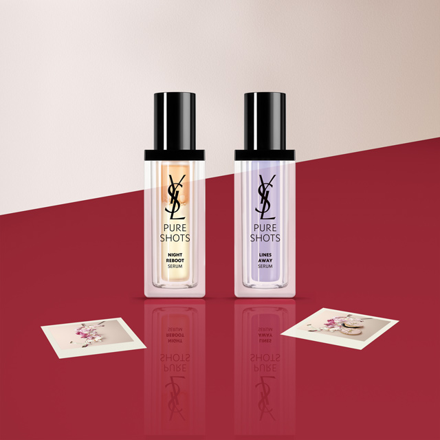 Tre miniature di profumi Yves Saint Laurent (YSL) in bottiglie bianche e trasparenti, possibilmente Libre, Black Opium e Mon Paris, esposte su una superficie rossa con piccole carte logo YSL.