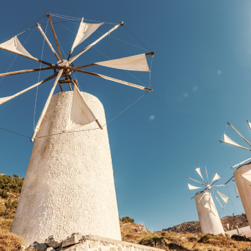 Traditional windmills on a hill under a clear sky.