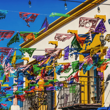 A colorful building in Los Cabos decorated with vibrant paper garlands under a clear sky.