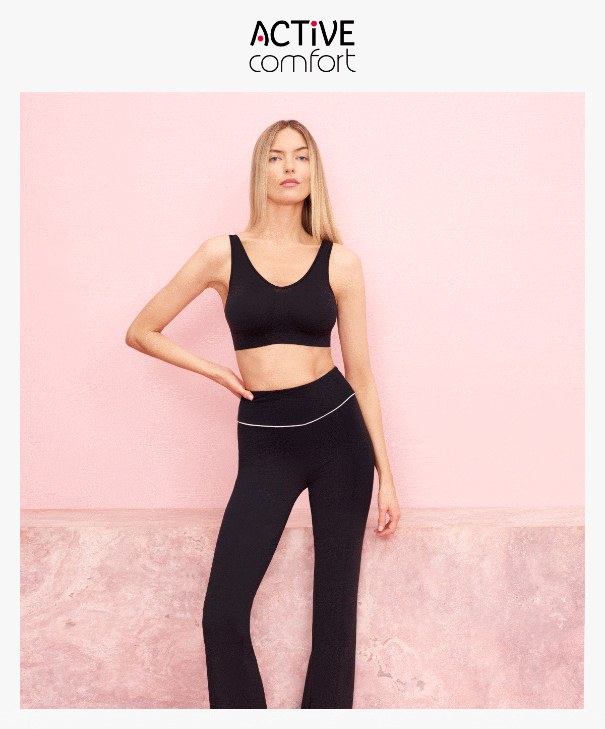 Modella indossa top e leggins sportivi neri, con scritta Active Comfort