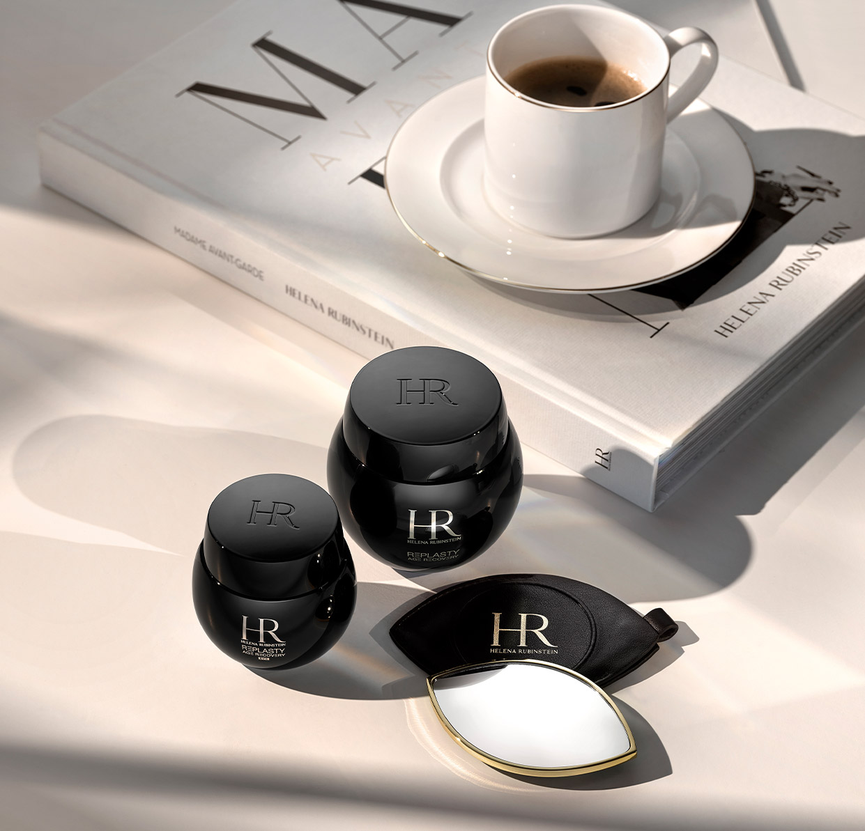 Prodotti Re-Plasty accanto a un libro su Helena Rubinstein con sopra una tazza di caffè, in una luce morbida.