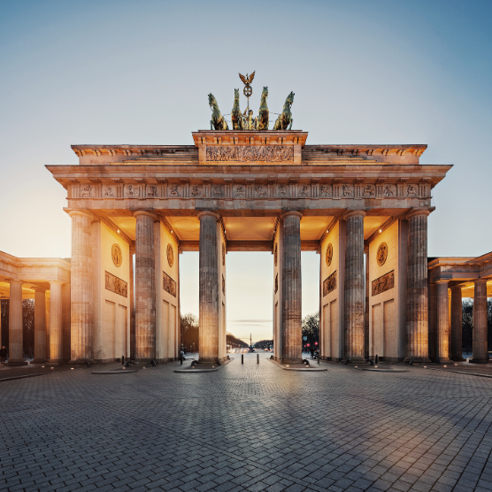 Monumental city gate with columns and a sculpture on top, captured in the evening light. Brandenburger Tor.