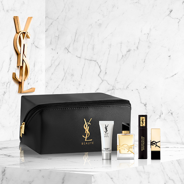Un'elegante pochette make-up nera YSL Beauté, con il logo YSL dorato, è esposta su una superficie in marmo bianco. Accanto ad essa ci sono un siero YSL Pure Shots, una bottiglia di profumo Mon Paris, un mascara e un rossetto, tutti a marchio YSL.