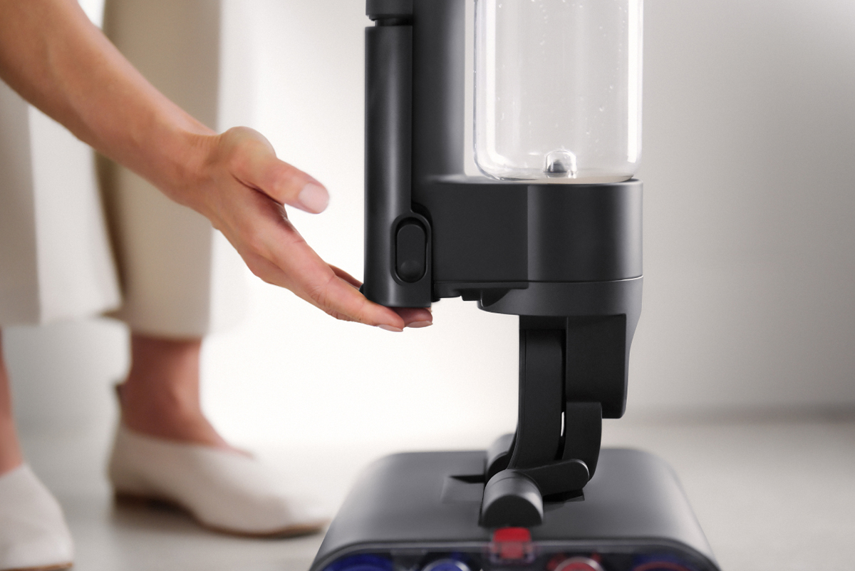 A user touching the Dyson Wash G1 wet cleaner's battery pack.