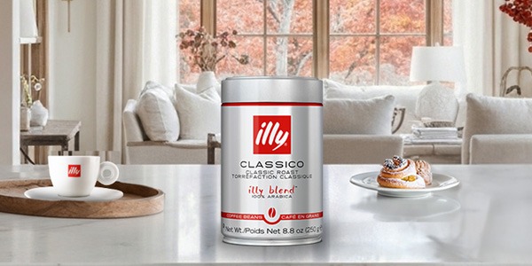 Can of illy coffee on a counter with a woman carrying an illy travel mug