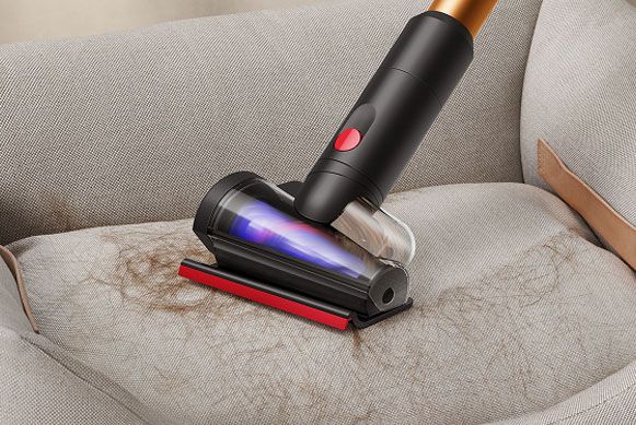 La mini turbo spazzola anti-groviglio 2.0 viene utilizzata per pulire una poltrona.