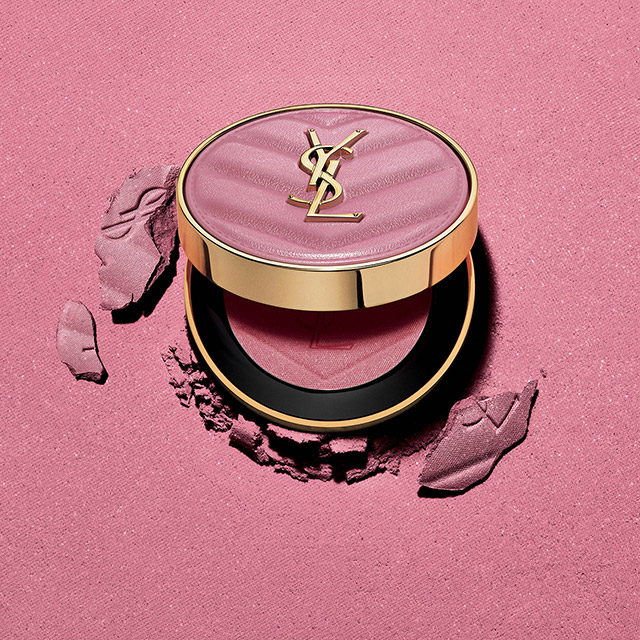 Una cipria compatta rosa YSL con il logo e prodotto sbriciolato.