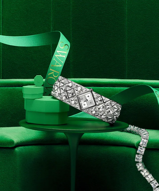 Orologio e gioielli Swarovski con una confezione regalo verde posati su un tavolo verde su sfondo verde Orologio e gioielli Swarovski con una confezione regalo verde posati su un tavolo verde su sfondo verde