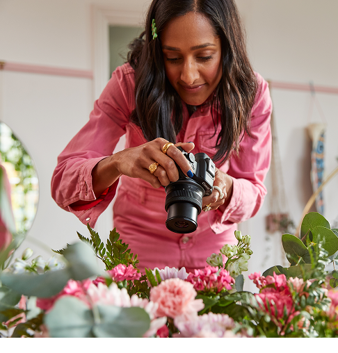 Una donna che fotografa fiori con una fotocamera Canon