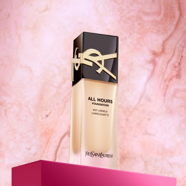 Flacone di fondotinta Yves Saint Laurent All Hours Mat Lumineux, posizionato su una piattaforma fucsia davanti a uno sfondo marmorizzato rosa
