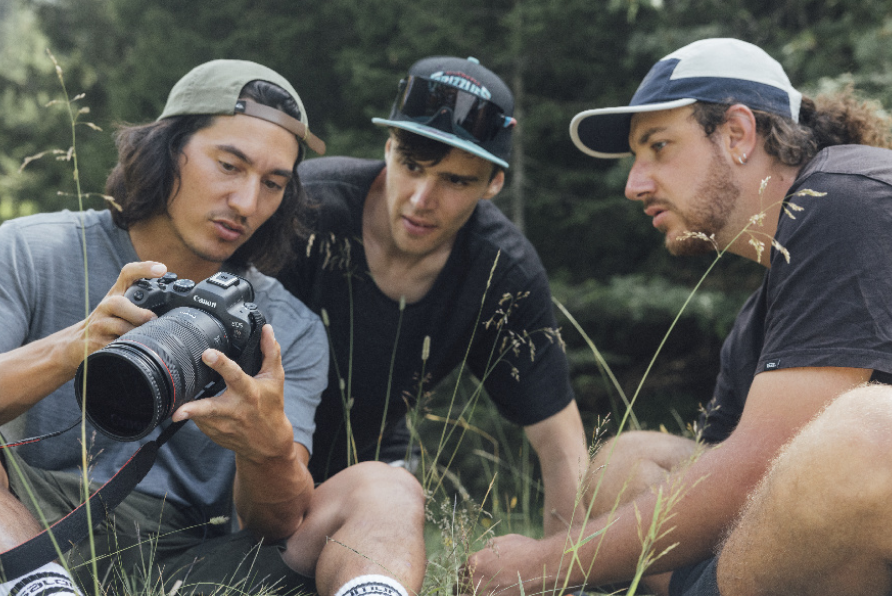 Tre uomini che guardano nel mirino di una fotocamera Canon