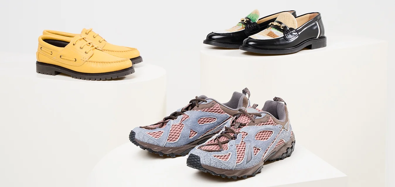 Scarpe da barca gialle in pelle, mocassim neri con dettagli decorativi e scarpe da ginnastica in mesh grigio/rosa su pedane bianche.