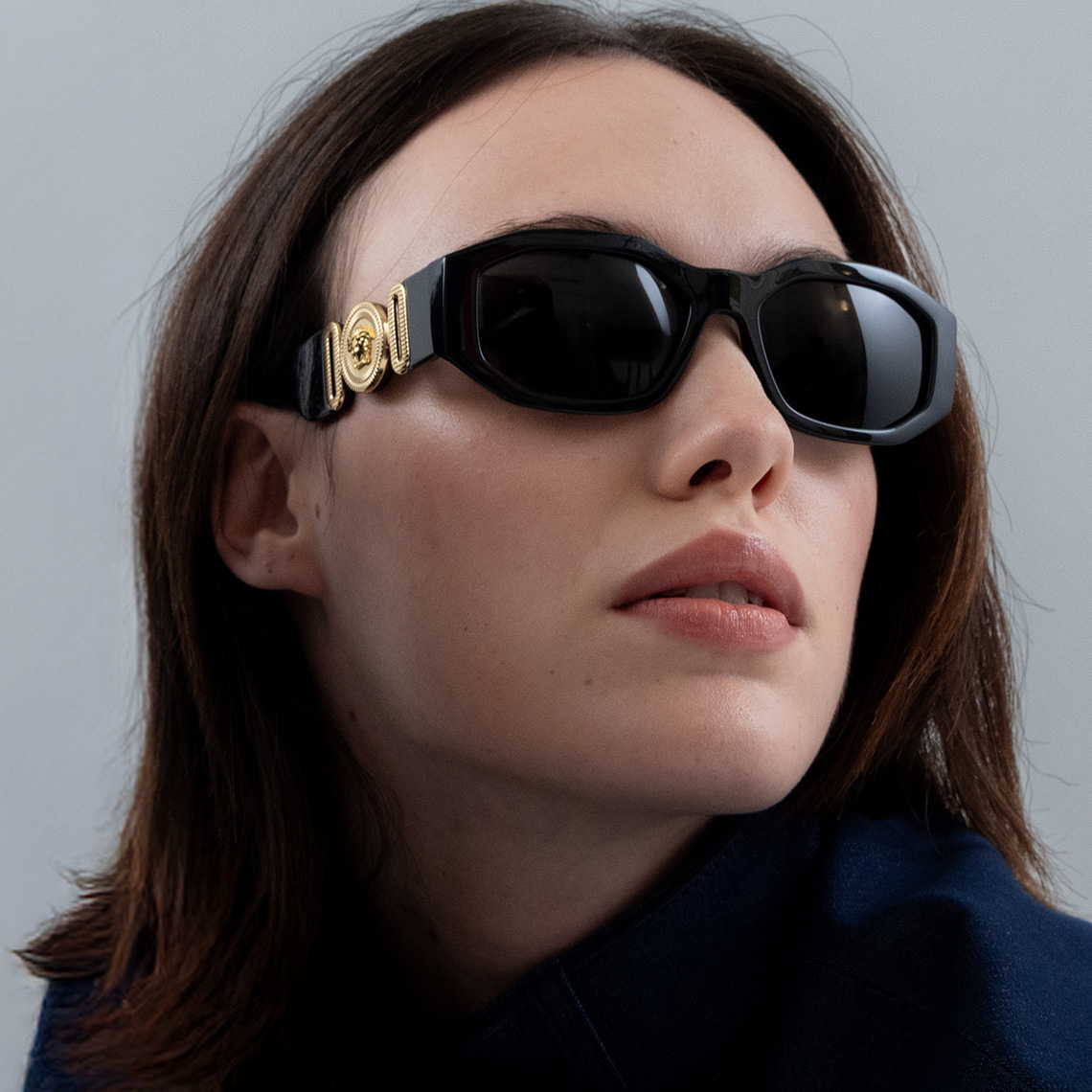 a woman wearing black sunglasses and a gold cuff around her neck