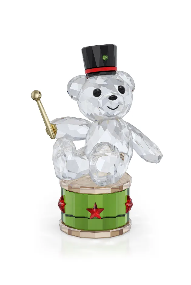 Orsetto Kris con cilindro seduto su un tamburo, con una bacchetta in mano