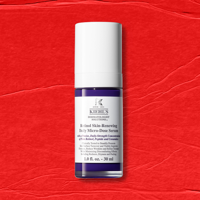 Flacone cilindrico bianco e viola di Kiehl’s Retinol Skin-Renewing Daily Micro-Dose Serum, su sfondo rosso.