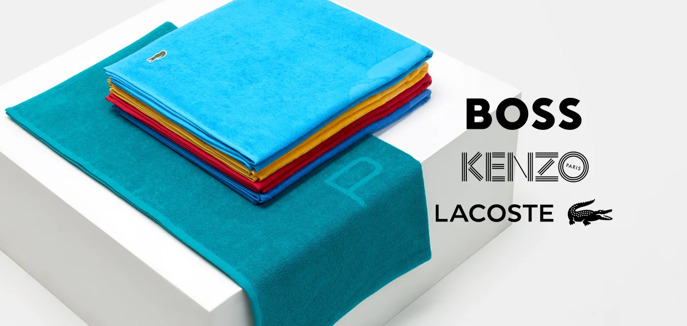 Set di asciugamani turchesi, con una pila di panni colorati in rosso, giallo e blu, posizionati su una scatola bianca con un asciugamano teal texturizzato drappeggiato accanto.