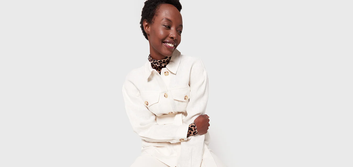 Completo beige chiaro composto da una camicia con bottoni e due tasche frontali, abbinata a pantaloni a gamba larga. Accentuato con un colletto e polsini in stampa leopardo.