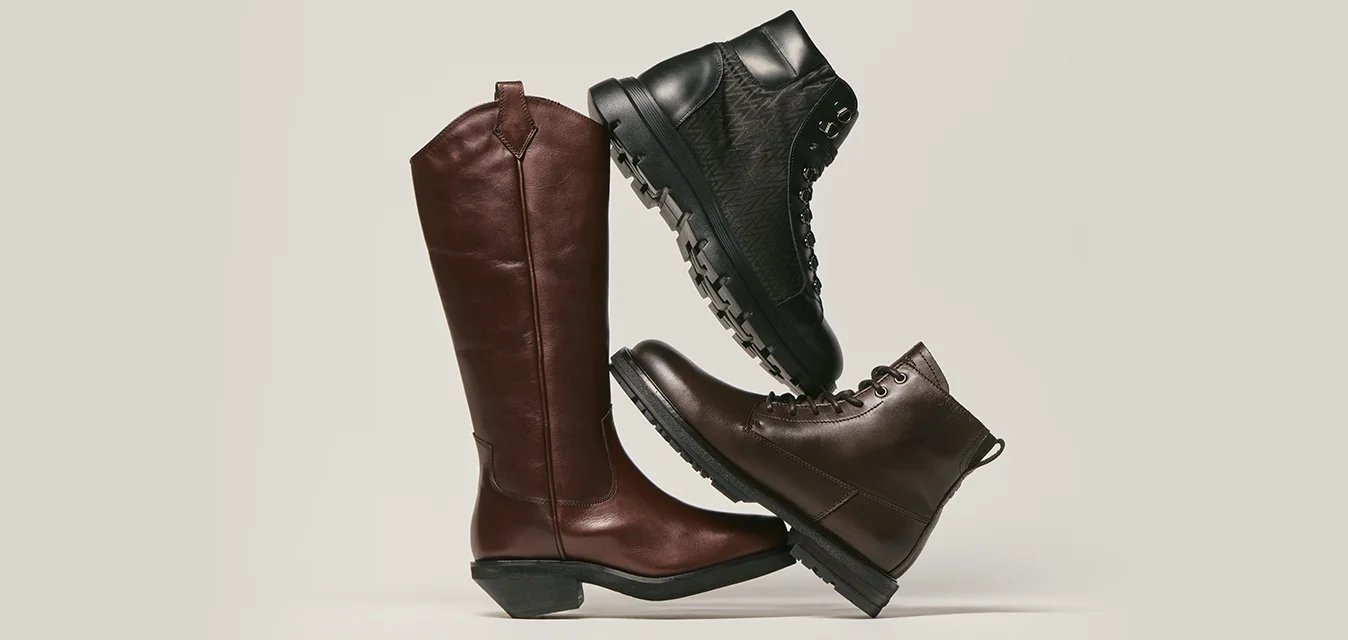 Tre stivali in pelle impilati: uno stivale da equitazione marrone alto, uno stivale da trekking nero e uno stivale alla caviglia marrone scuro.