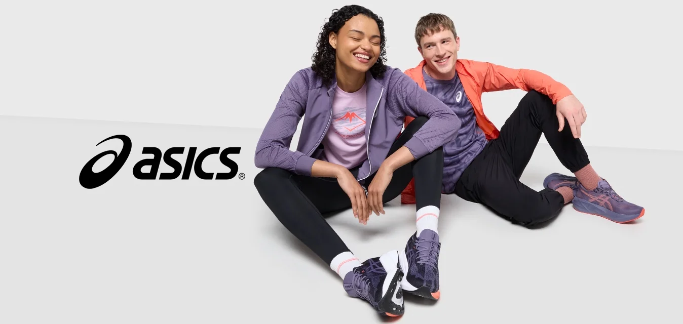 Due persone sedute su una superficie bianca, vestite in abbigliamento sportivo: giacca viola, top rosa, leggings neri e scarpe multicolori.