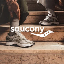 Sneaker bianchi e grigie con pannelli in mesh testurizzati, dettagli neri e lacci bianchi. Indossati con pantaloni grigi e verdi su gradini in pietra.