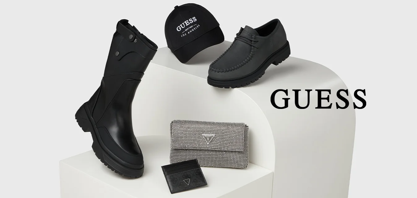 Stivali neri impermeabili, scarpe in pelle grigia, cappello nero con logo e portafoglio a fantasie esposti su un piedistallo curvo bianco.