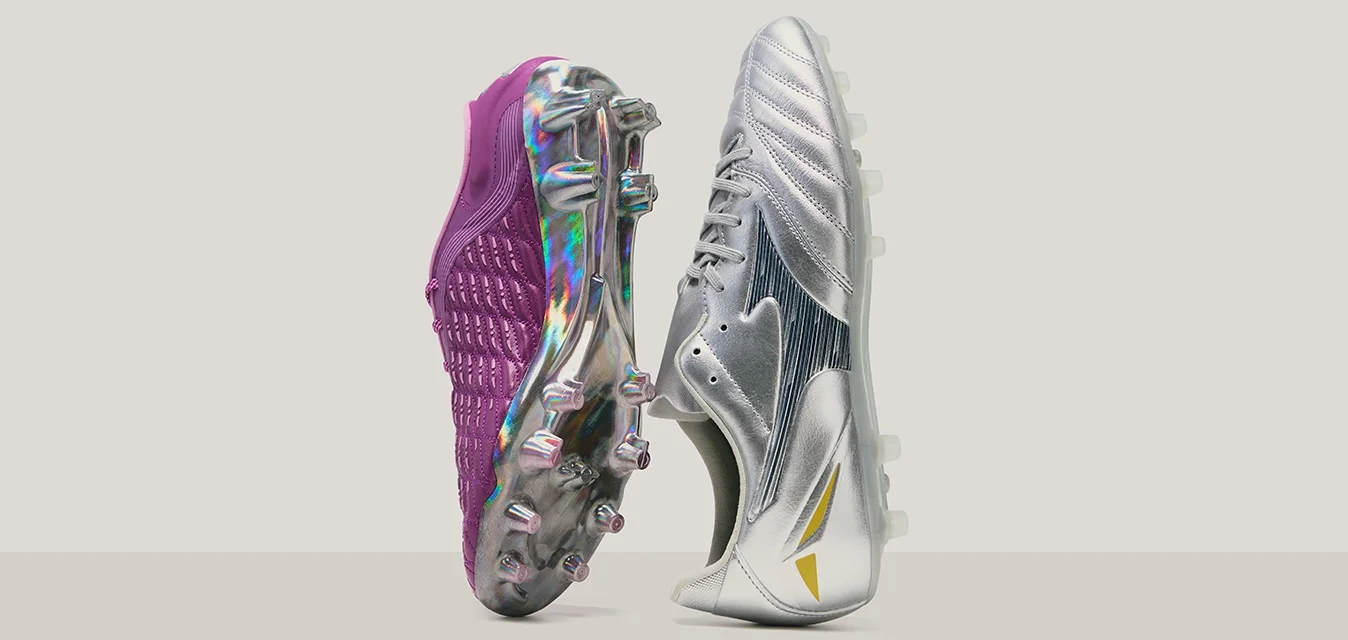 Scarpe da calcio con una tomaia in tessuto testurizzato viola e un design argentato lucido con dettagli, entrambe dotate di tacchetti stampati per garantire aderenza.