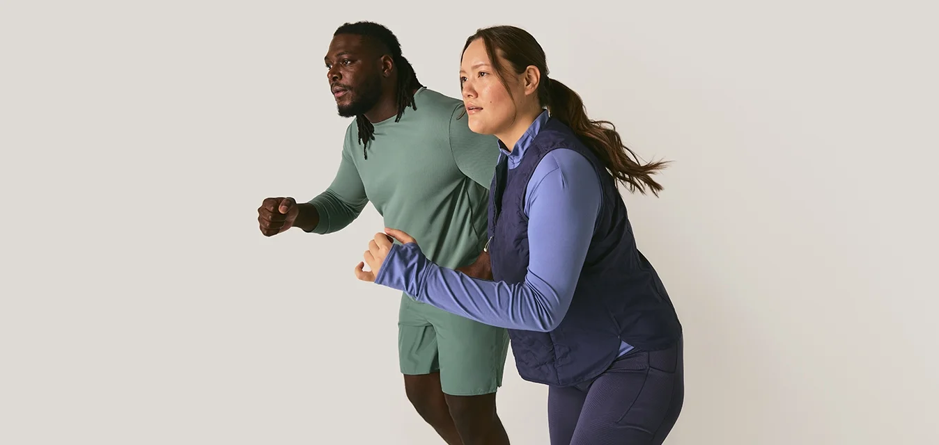 Uomo e donna in abbigliamento sportivo posizionati come se fossero pronti a correre, su uno sfondo chiaro e semplice.