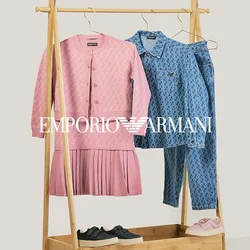 Stendino per abiti in legno con vestito lavorato a maglia rosa e cardigan, camicia blu a fantasia e jeans, sneaker nere e rosa sopra e sotto il rack.