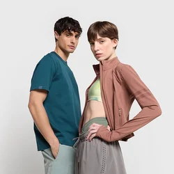 Maglietta teal a maniche corte e reggiseno sportivo verde chiaro abbinati a una giacca rosa aderente con zip e pantaloni sportivi grigi con accenti a fantasia.