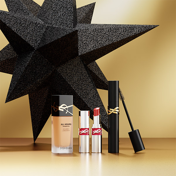 Prodotti YSL Beauté, inclusi il fondotinta All Hours, due rossetti e un mascara, sono esposti su uno sfondo dorato con una stella nera scintillante.