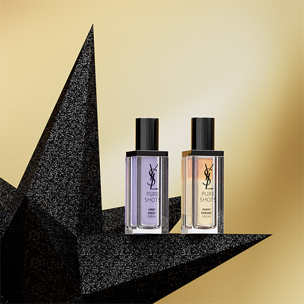Due sieri YSL Pure Shots, Lines Away e Night Reboot, sono esposti su una stella nera scintillante contro uno sfondo dorato.