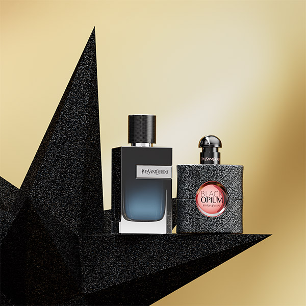 I profumi YSL, Y for Men e Black Opium, sono esposti su una stella nera scintillante contro uno sfondo dorato.