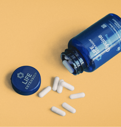 alt="Life Extension Flacone di glicina su sfondo giallo con capsule bianche versate accanto al coperchio aperto.»