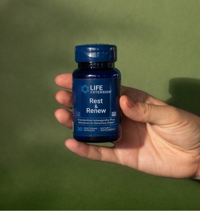 alt="Mano che tiene in mano una bottiglia Life Extension Rest & Renew su uno sfondo verde tenue, illuminato dalla luce solare naturale.»