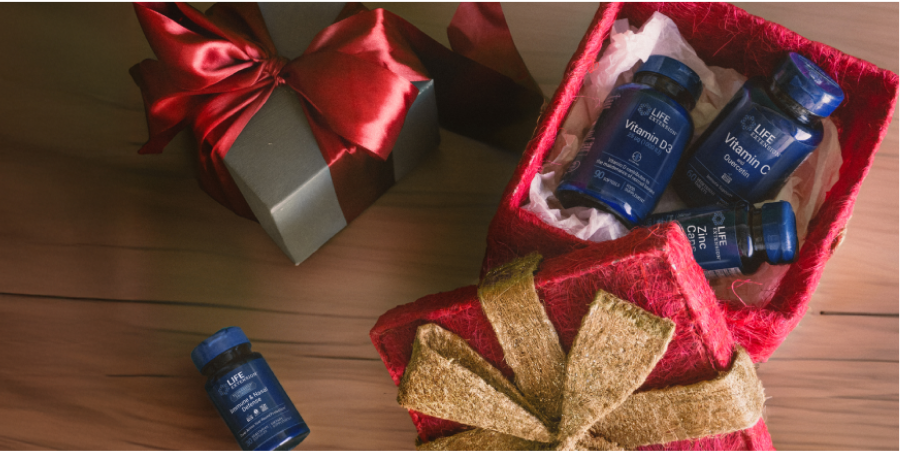 alt="Regali di Natale incartati e confezioni regalo aperte piene di flaconi di integratori Life Extension. "»