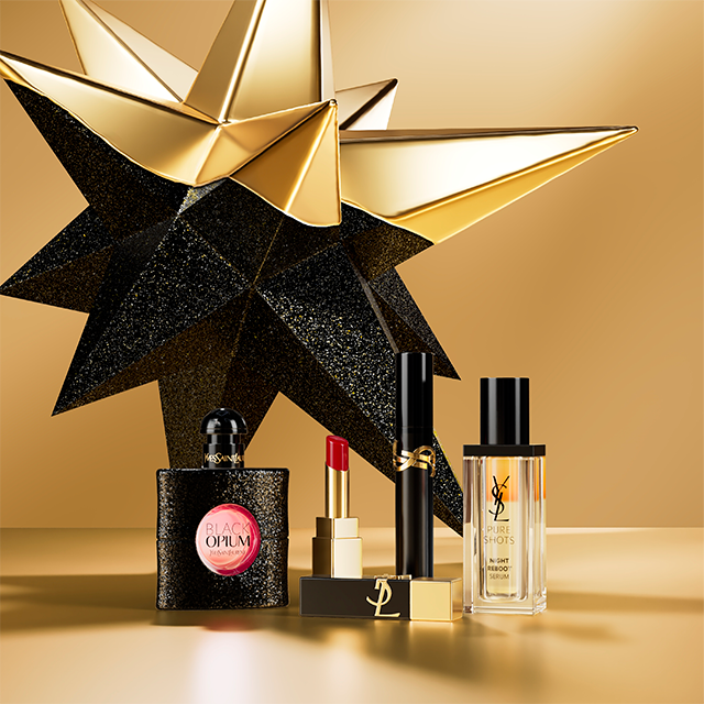 Un'esposizione lussuosa di prodotti Yves Saint Laurent Beauté, inclusi il profumo Black Opium, un rossetto, un mascara e il siero Pure Shots Night Reboot, ambientata su uno sfondo dorato con una grande stella stilizzata oro e nera.