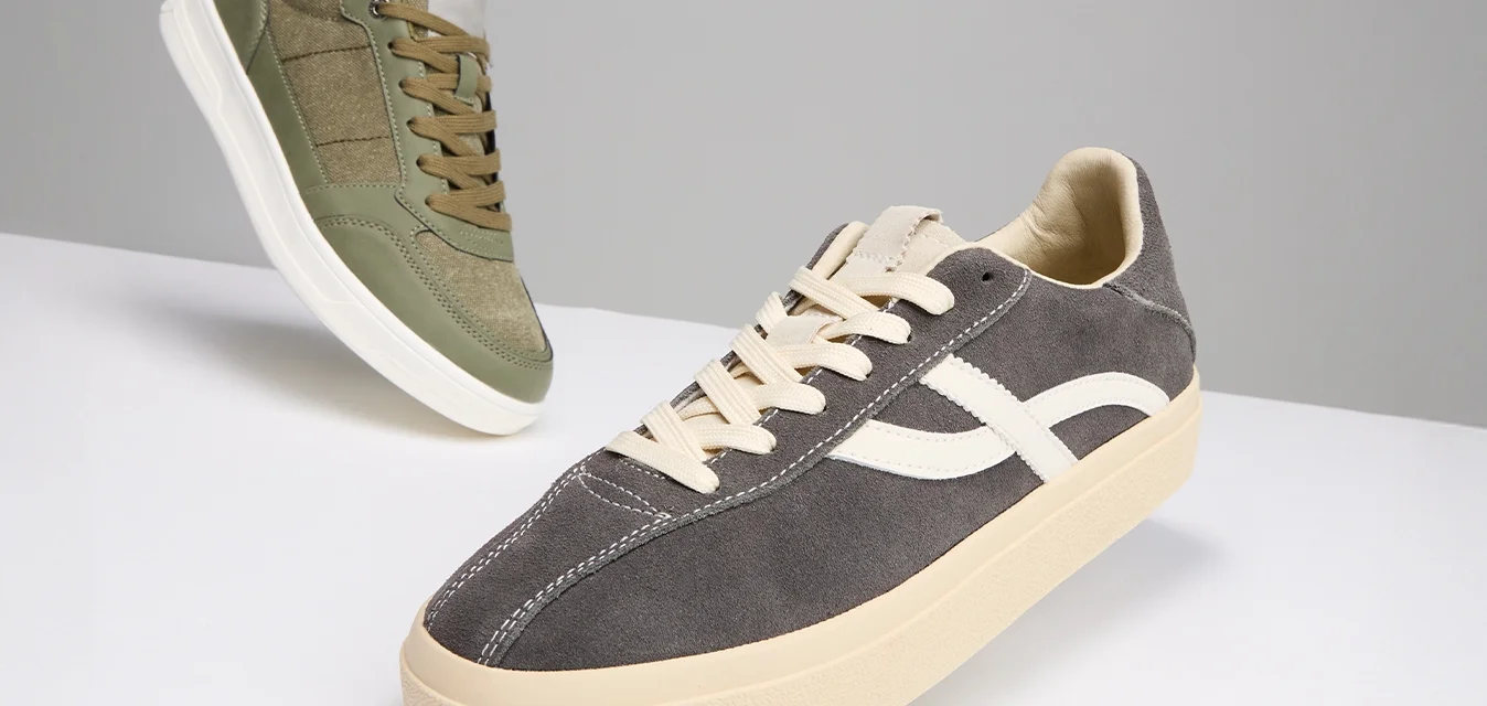 Due paia di sneaker: una verde oliva con una miscela di camoscio e tela, e una grigia scura in camoscio con una striscia bianca testurizzata e suola crema.